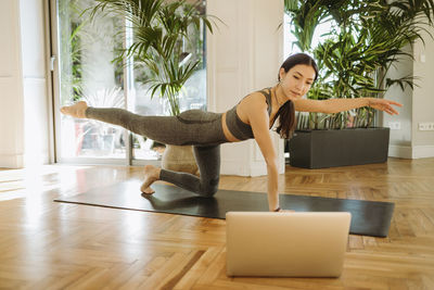 Young woman sitting on hardwood floor at home