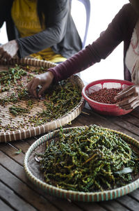 Midsection of man preparing food in basket on table