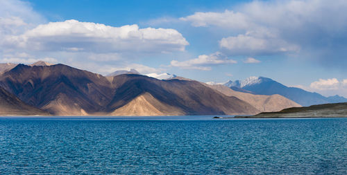 Scenic view of lake and mountains against cloudy sky