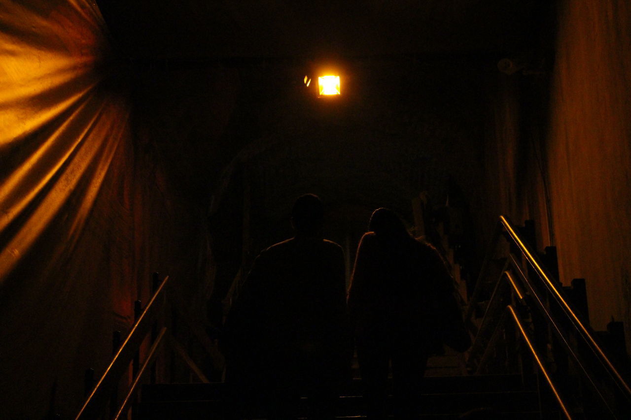 REAR VIEW OF PEOPLE STANDING BY RAILING