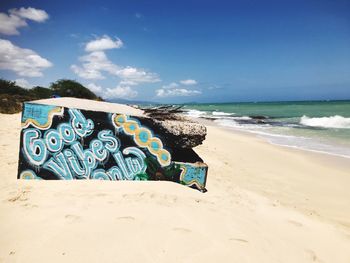 Graffiti on beach against blue sky