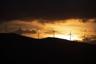 Silhouette electricity pylon against sky during sunset