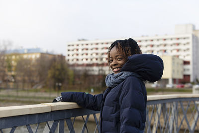 Portrait of smiling young woman while standing by canal