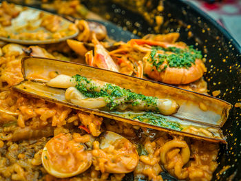 Traditional spanish seafood dish called paella in a black pan with clams and shrimp on a pad of rice