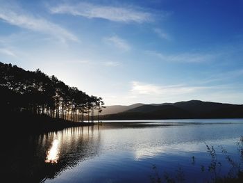 Scenic view of lake by silhouette mountain against sky