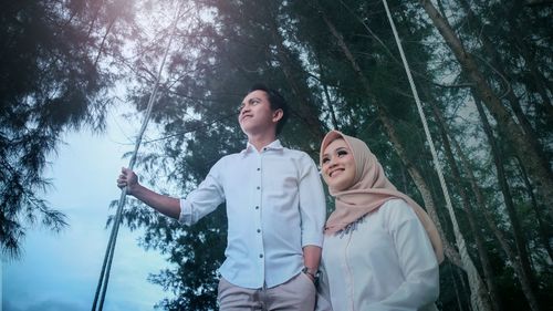 Low angle view of young woman standing in forest