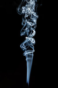 Close-up of burning candle against black background