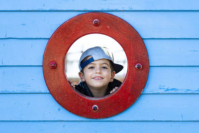 Portrait of smiling boy looking through circle shaped window