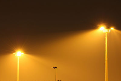 Low angle view of illuminated street lights against sky during sunset