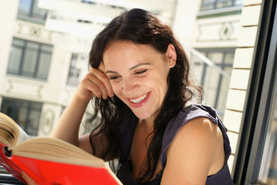 Portrait of smiling young woman sitting on book