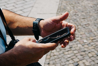 Midsection of man using mobile phone on street