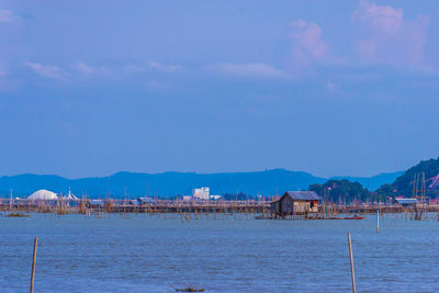 Scenic view of sea by houses against sky