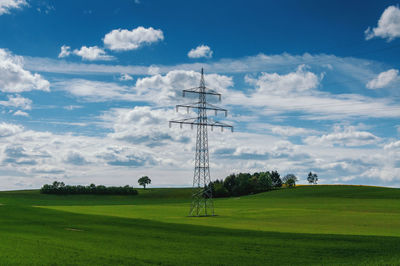 Electricity pylon on field against sky