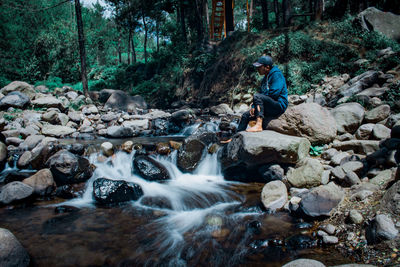 Man sitting on rock in forest