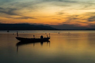 Silhouette boats in sea against orange sky