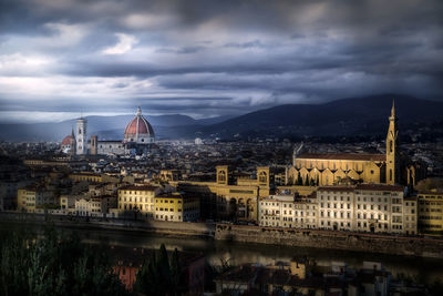 Illuminated buildings in city against cloudy sky,l