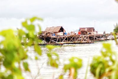 Stilt house in water against sky