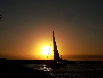 Silhouette boat sailing in sea against sky during sunset