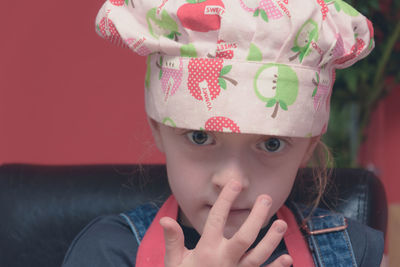 Close-up portrait of girl wearing chef hat at home