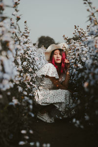 Woman in dress crouching amidst plants