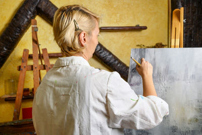 Rear view of painter painting at home