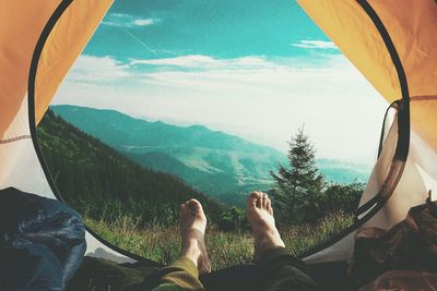 Low section of hiker lying in tent against mountains