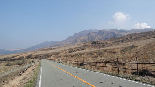 Road leading towards mountains against sky