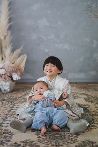 Portrait of boy and baby sitting on field. kimono