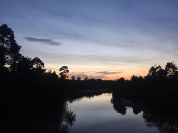 Silhouette trees by lake against sky during sunset