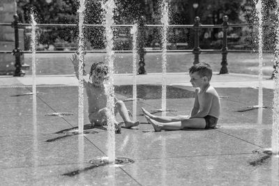 Siblings playing by water fountain