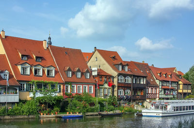 Buildings by river against sky