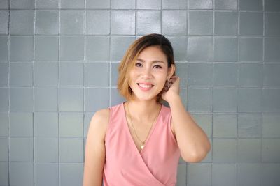 Portrait of a smiling young woman against wall