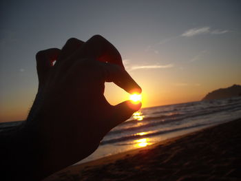 Close-up of silhouette hand against sky during sunset