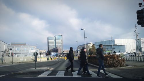 People walking on road in city against sky