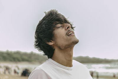 Close-up of young man with eyes closed standing at beach