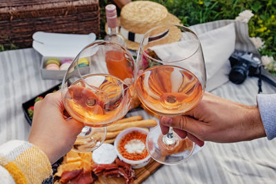 Couple clinking with two glasses of rose wine. romantic summer picnic outdoors in french style