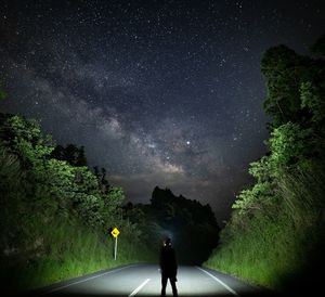 Rear view of man on road against sky at night
