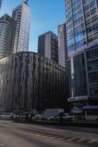 Road by buildings in city against sky