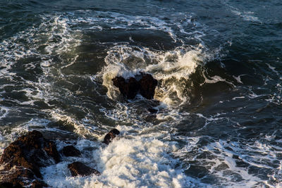 High angle view of waves breaking on rocks