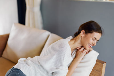 Young woman using mobile phone while sitting on sofa at home