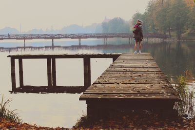 Woman standing on pier over lake