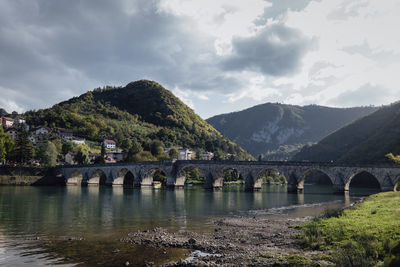 Arch bridge over river against sky