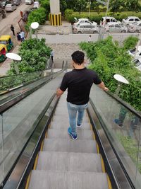 Rear view of mid adult man standing on escalator