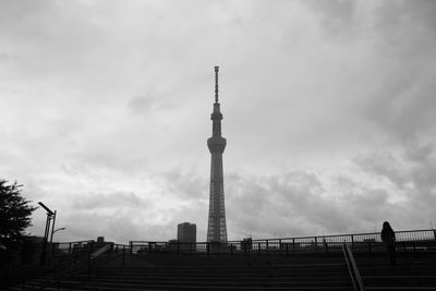 Low angle view of communications tower and buildings against sky