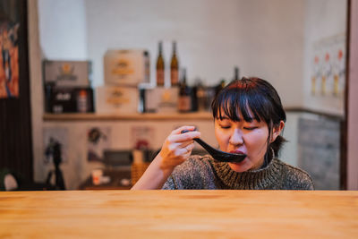 Portrait of woman holding mobile phone while sitting on table