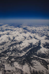 Aerial view of snowcapped mountains against blue sky