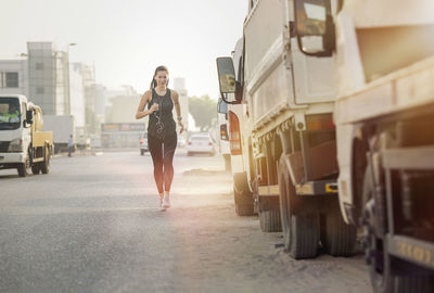 Full length of woman running by vehicle on road