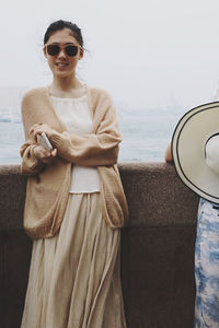 Young woman wearing sunglasses while standing against sky