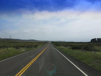 Empty road passing through field