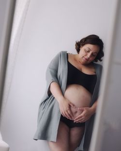 Woman looking away while standing against wall